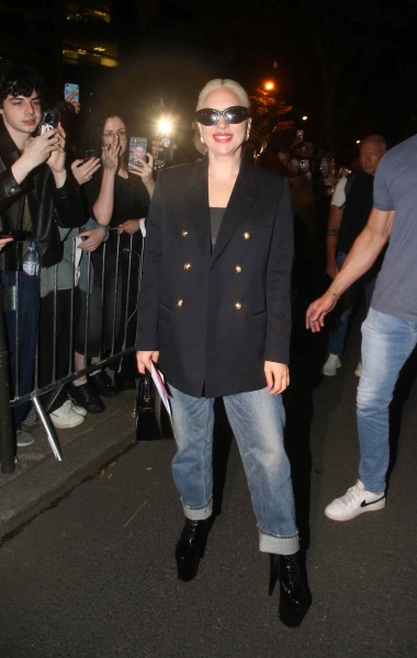 Look of the Day for July 26, 2024 features Lady Gaga in mid-wash, boyfriend jeans with rolled up ankles, a black shell top, blazer, sunglasses and high-heeled boots while out in Paris for the Summer Olympics