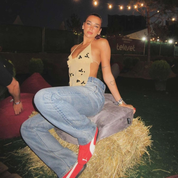 Dua Lipa wore a sheer tan halter top to the third night of the Sunny Hill Festival. See her full look, including her fiery red sneakers, here.