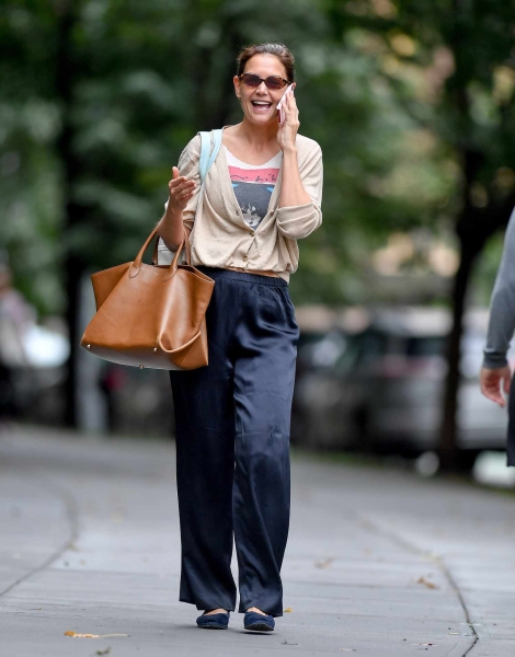 Look of the Day for September 3, 2024 features Katie Holmes in blue silk pants, beige oversized cardigan, graphic tee, and velvet Mary Jane ballet flats while out and about in New York City.