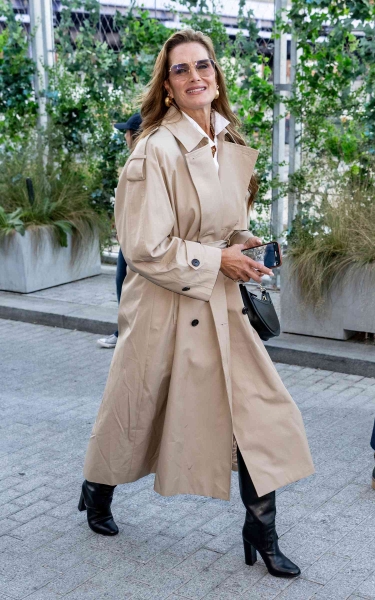 Look of the Day for September 9, 2024 features Brooke Shields in a oversized khaki-colored trench coat and knee-high black boots while at Tommy Hilfiger’s summer 2025 fashion show in New York City.