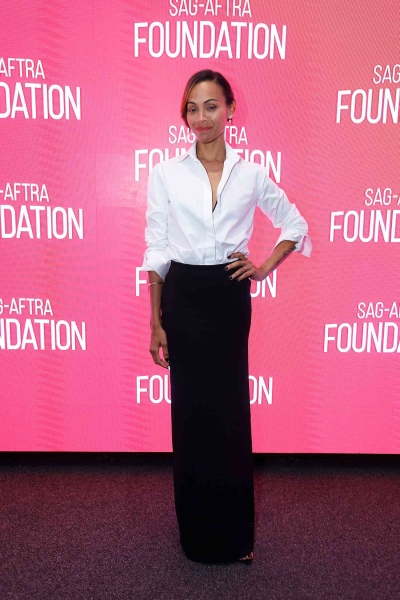 Look of the Day for October 16, 2024 features Zoe Saldaña in a black maxi column skirt, white button-down, and black mesh heels for a red carpet event.