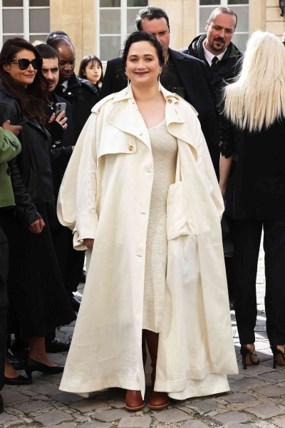 Look of the Day for September 30, 2024 features Lily Gladstone in a knit dress and trench coat during Paris Fashion Week.