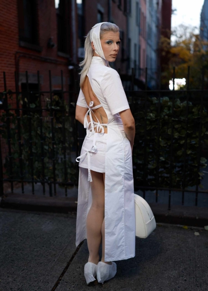 Julia Fox was spotted in New York City in another sartorial creation that broke all of the fashion rules—this time, a white apron dress that was completely backless paired with a white bandage-inspired headband.