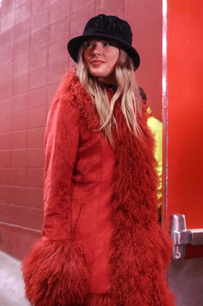 Taylor Swift bundled up in a Chiefs-red winter coat and a black fuzzy bucket hat to cheer on Travis Kelce at the Chiefs vs. Texans game on Saturday, December 21. See her game-day outfit, here.